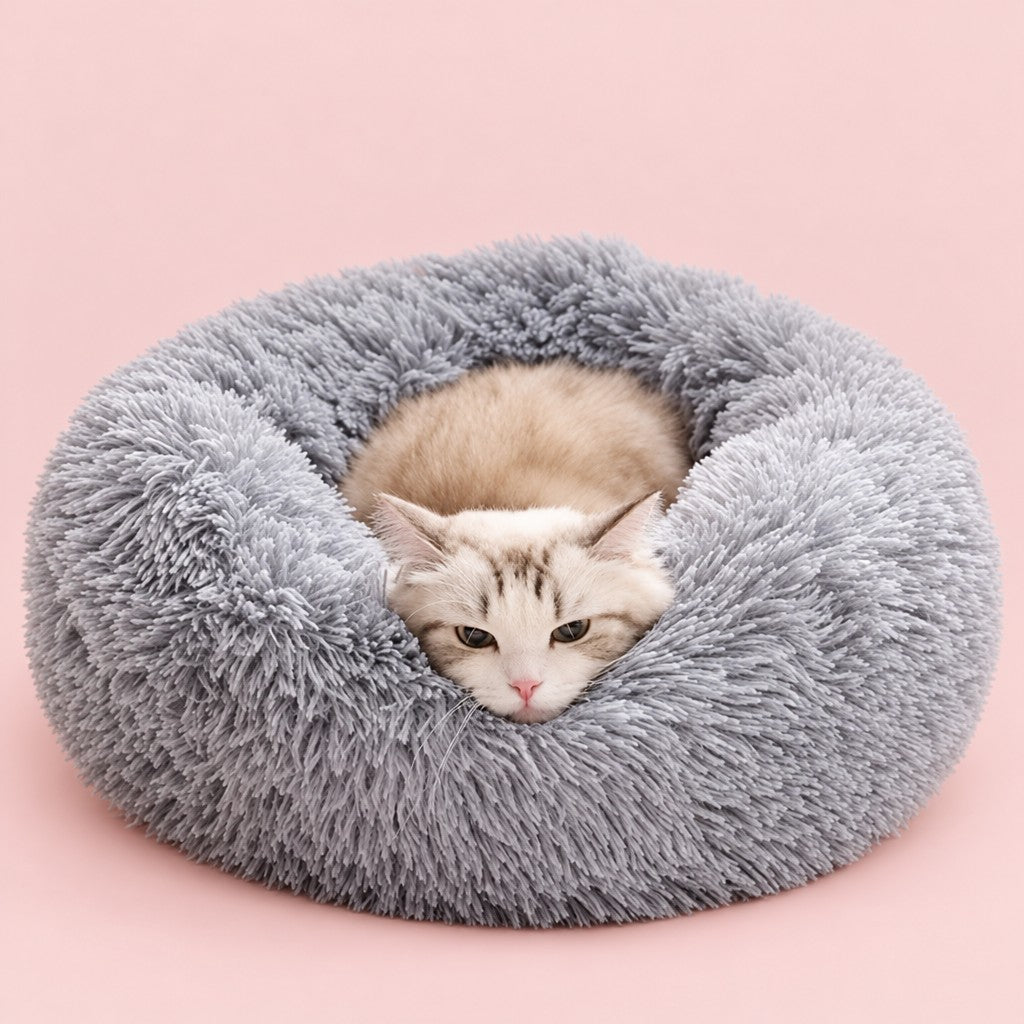 Grey faux fur donut pet bed with a cat curled up inside, on a blush pink background