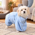 A fluffy white dog wearing the quick-drying blue towel robe for dogs in a cosy living room