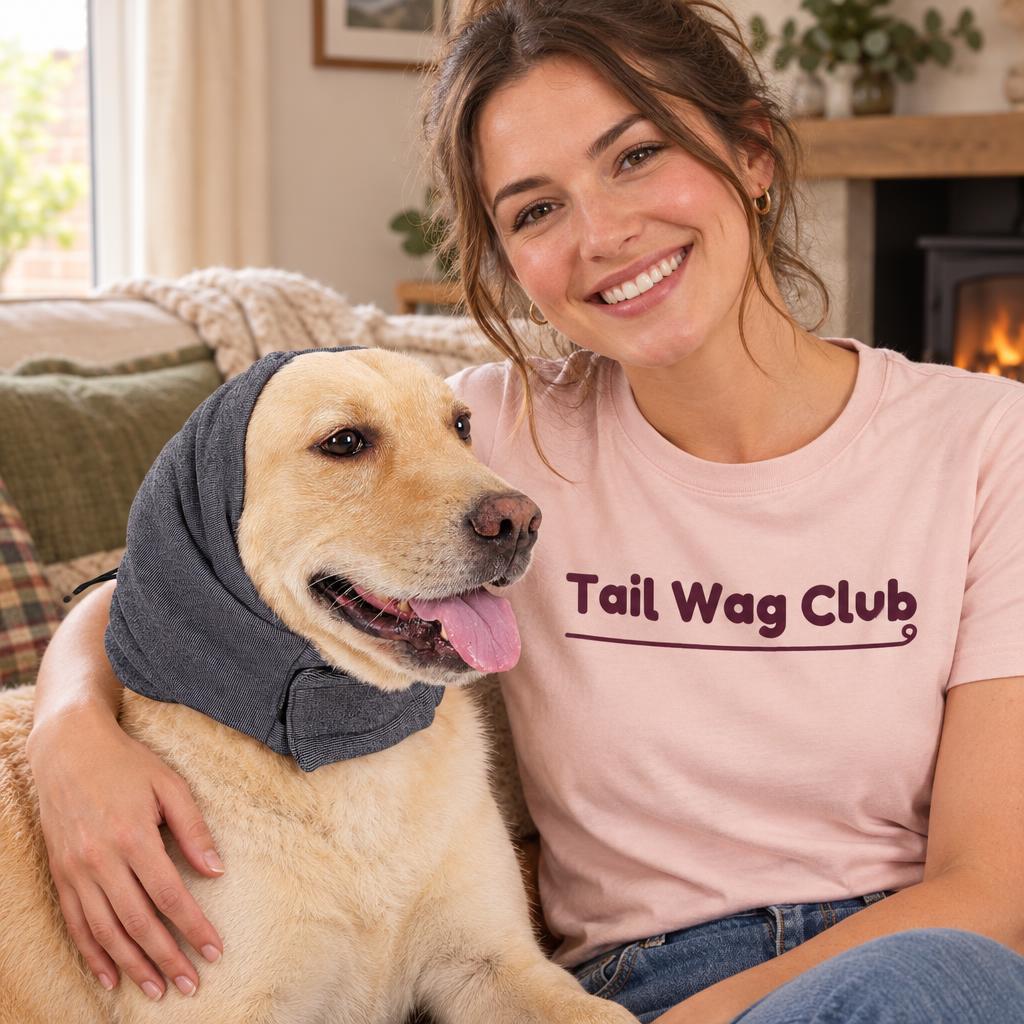 [lifestyle] Smiling owner in a pink "Tail Wag Club" t-shirt with a yellow Labrador and the grey fleece dog ear snood