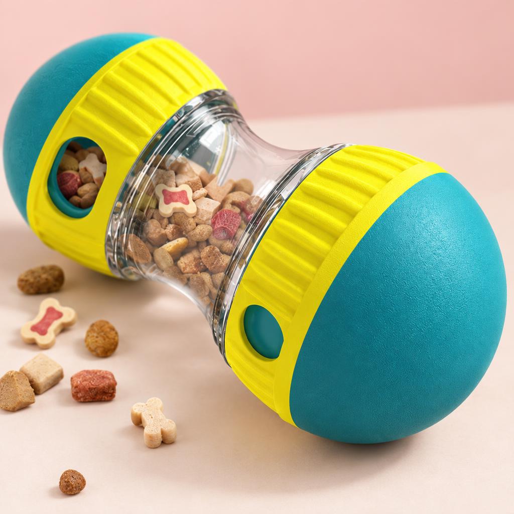 Close-up of the teal and yellow treat dispensing tumbler toy on a soft pink background