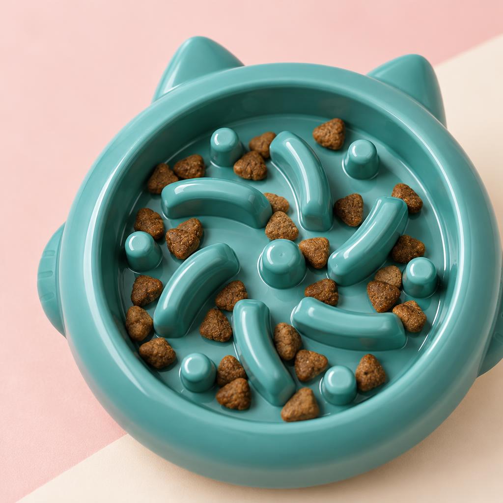 Close-up of the green cat-ear swirl slow feeder bowl on a soft pink background