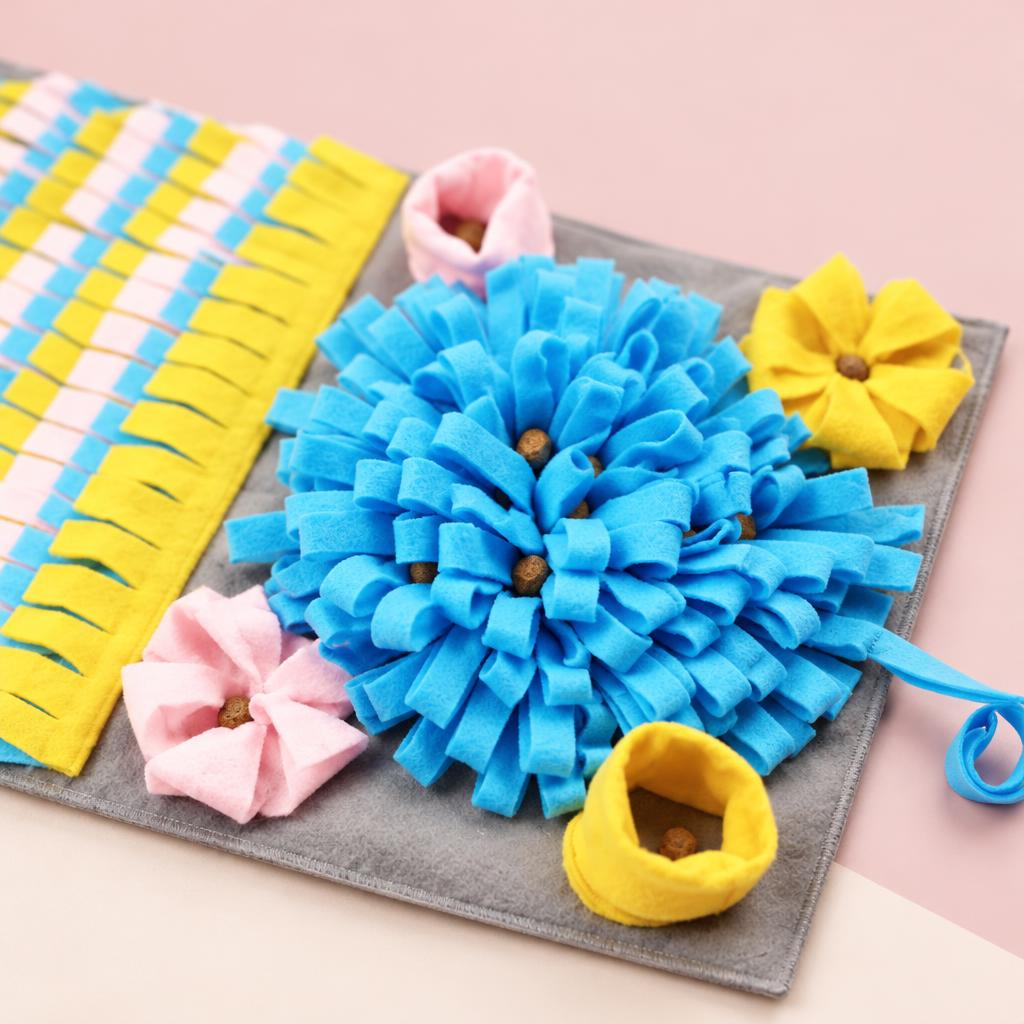 Close-up of the grey 3D snuffle mat with blue, yellow and pink fabric flowers on a soft pink background