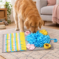 A golden retriever sniffing for treats on the grey 3D snuffle mat with blue, yellow and pink fabric flowers in a living room