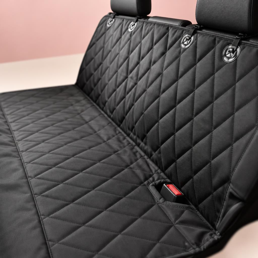 Close-up of the black quilted dog car seat cover on a back seat, with a red seat belt buckle in the safety exit slot