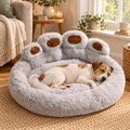 A small dog asleep in the light grey paw-shaped pet bed in a cosy UK living room by a window